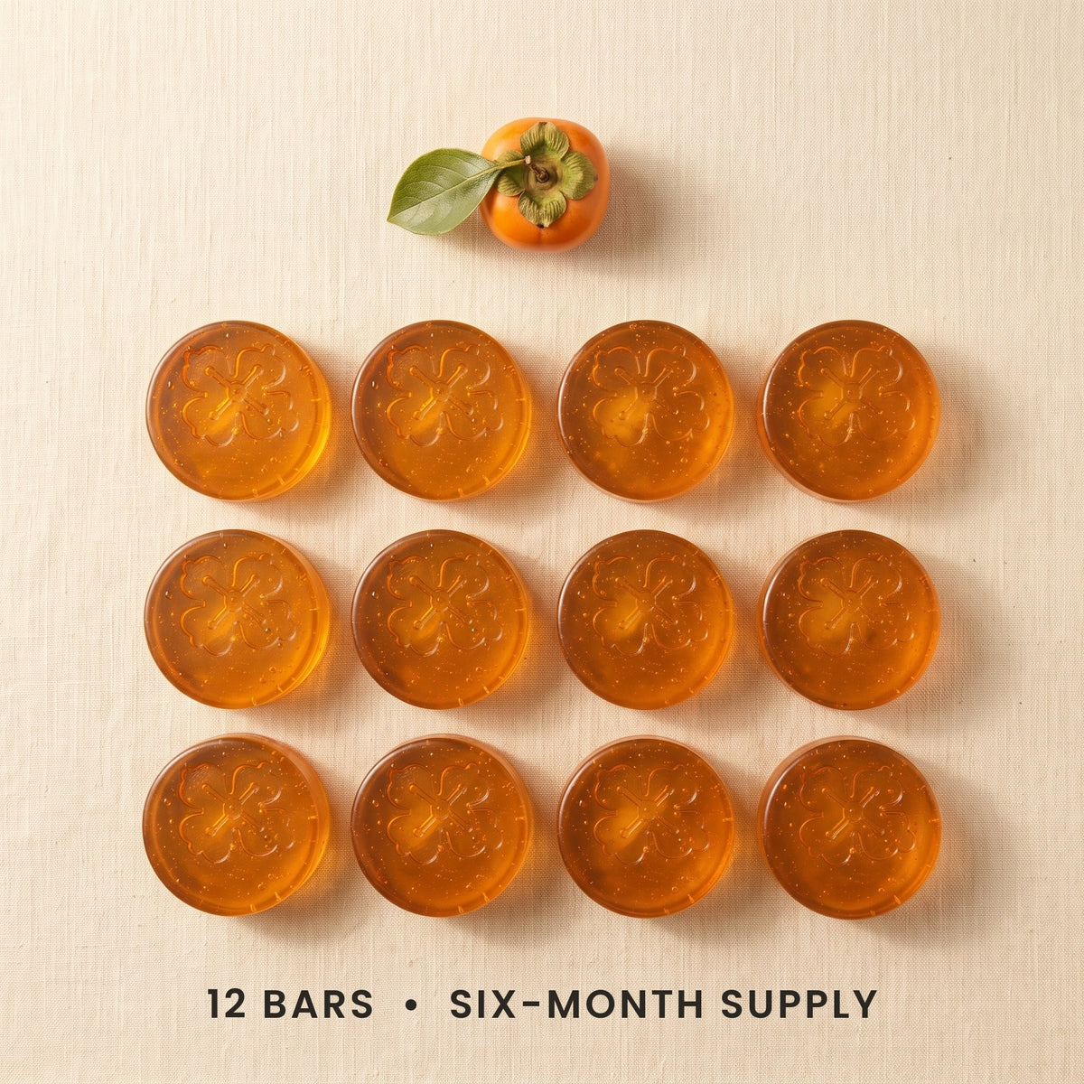 Twelve Kakiyu persimmon soap bars in a grid on cream linen, a six-month supply